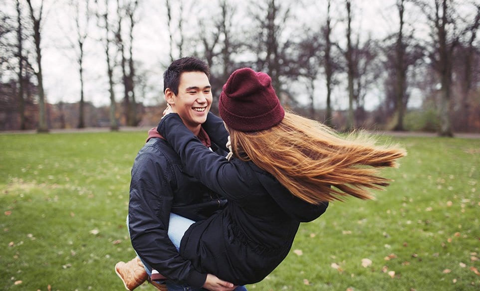 teen couple smiling and hugging in the forest