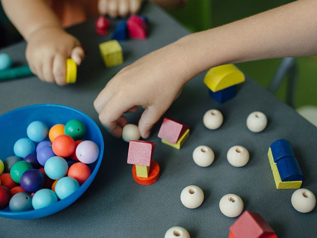 childrens hands playing with wooden toys